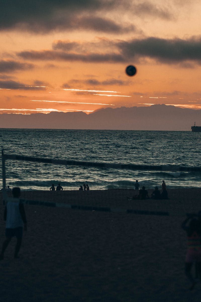 Silhouettes playing beach volleyball at sunset on Manhattan Beach, California.